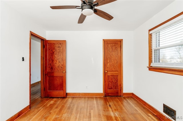 unfurnished room featuring light wood finished floors, baseboards, visible vents, and a ceiling fan