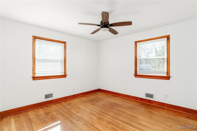 empty room featuring light wood finished floors, visible vents, and baseboards