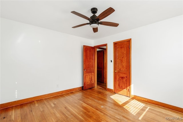 empty room featuring a ceiling fan, light wood-style flooring, and baseboards