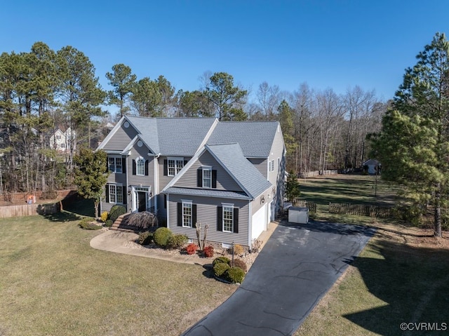 view of front of property featuring aphalt driveway, a garage, a front lawn, and fence