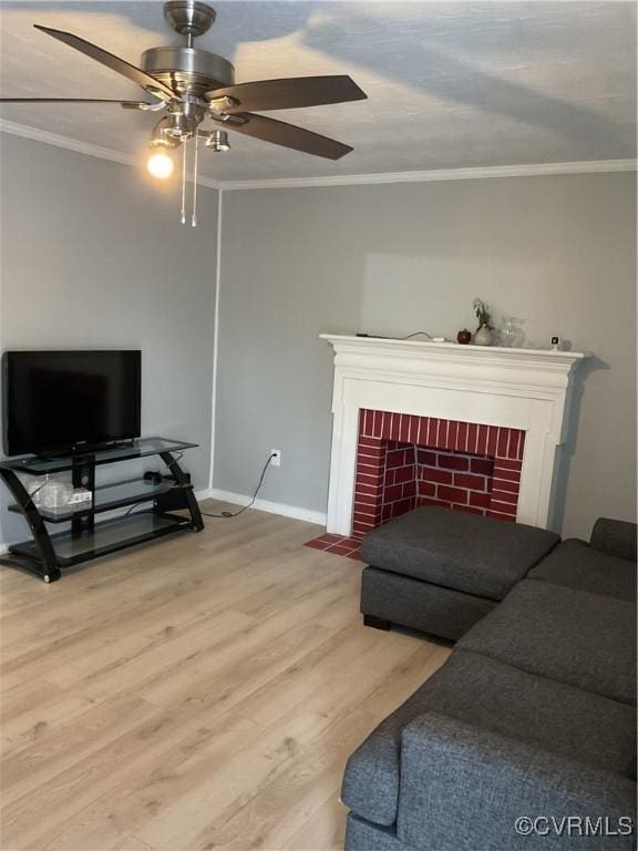 living room with baseboards, a ceiling fan, wood finished floors, crown molding, and a fireplace