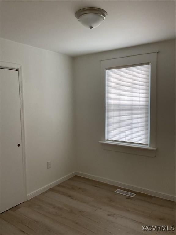 spare room featuring visible vents, light wood-style flooring, and baseboards