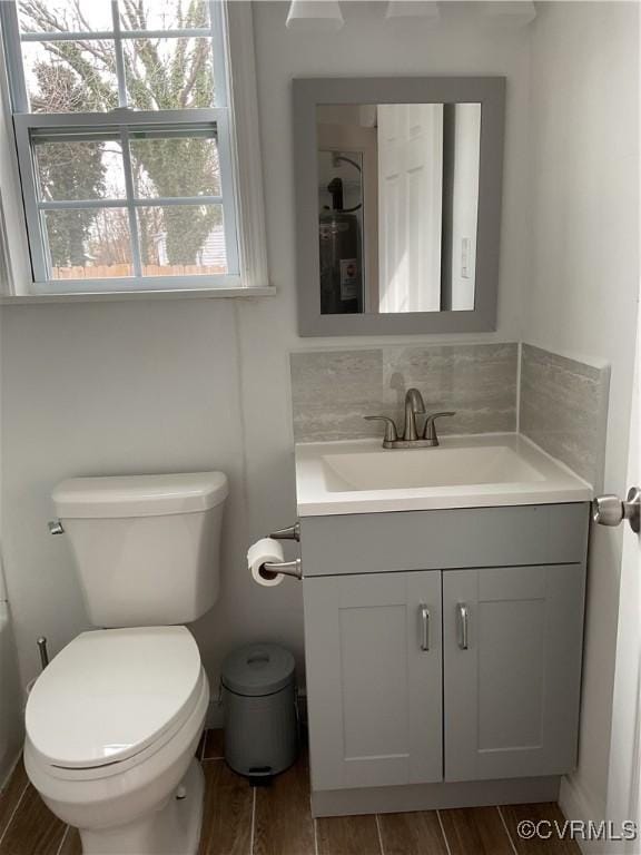 bathroom featuring decorative backsplash, wood finish floors, vanity, and toilet