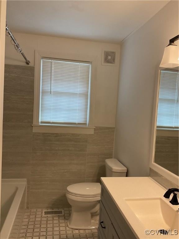 bathroom featuring tile walls, visible vents, vanity, and toilet