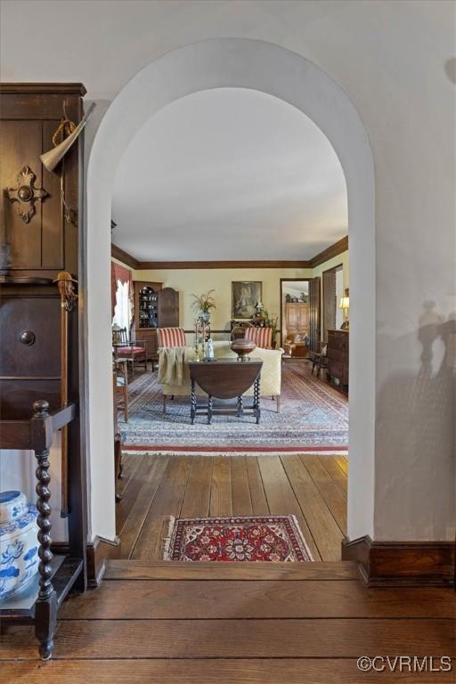 corridor with hardwood / wood-style floors, arched walkways, and ornamental molding