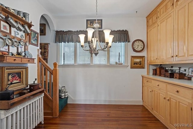interior space featuring arched walkways, dark wood-style flooring, baseboards, an inviting chandelier, and light countertops