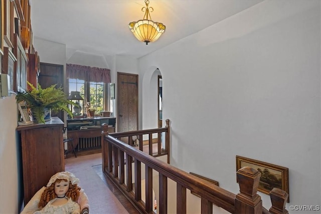 corridor featuring arched walkways and an upstairs landing