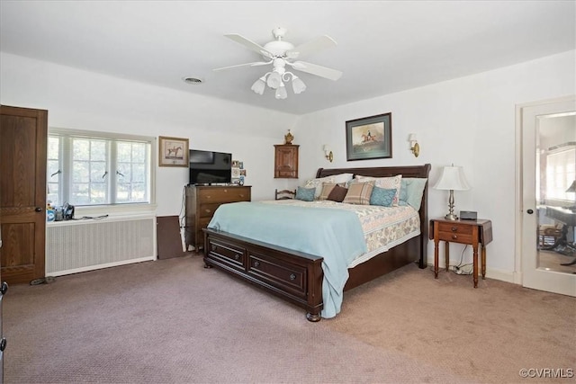 bedroom with a ceiling fan, light carpet, visible vents, and radiator heating unit