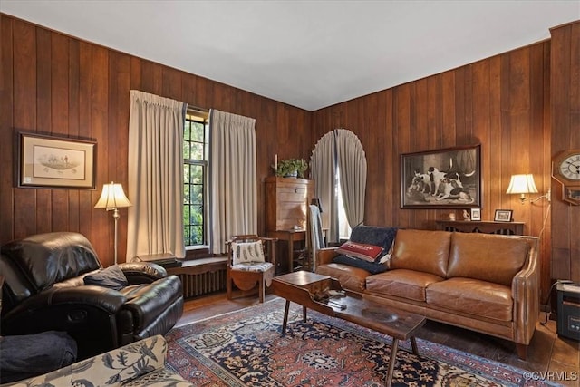 living area with radiator, wooden walls, and wood finished floors
