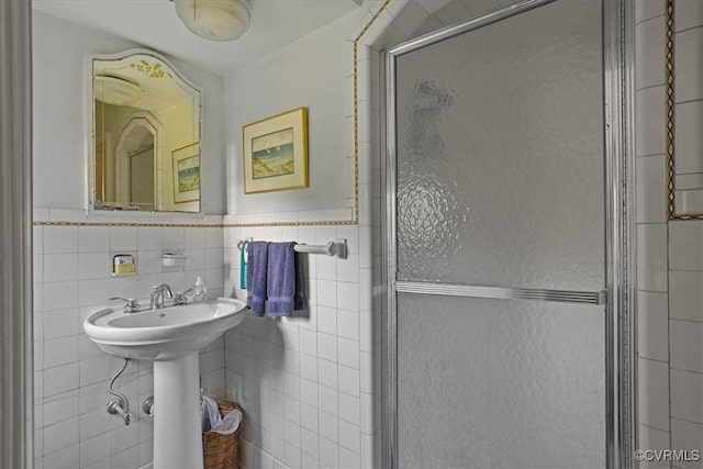 bathroom with tile walls, wainscoting, and a shower stall