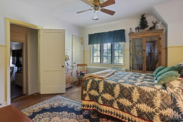 bedroom with ceiling fan, a wainscoted wall, and wood finished floors