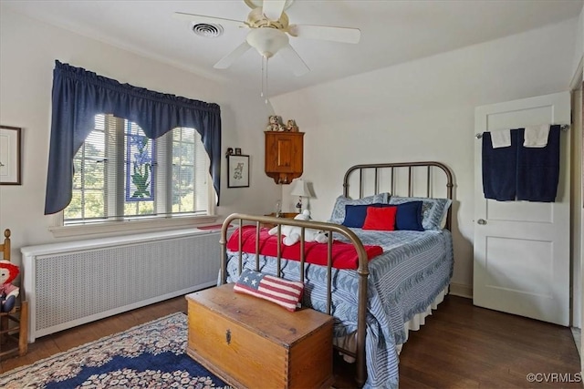 bedroom with radiator, ceiling fan, visible vents, and wood finished floors