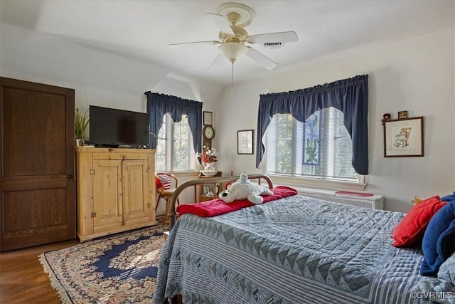 bedroom with a ceiling fan, wood finished floors, and visible vents
