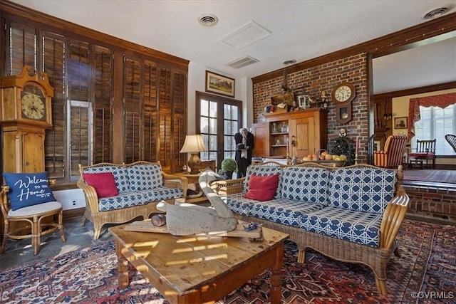 living area with brick wall, visible vents, and french doors