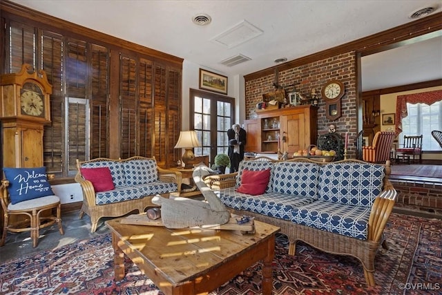 living area featuring brick wall, crown molding, and visible vents