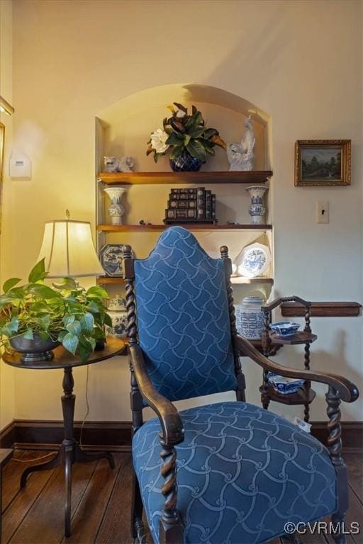 sitting room with built in shelves, baseboards, and wood finished floors