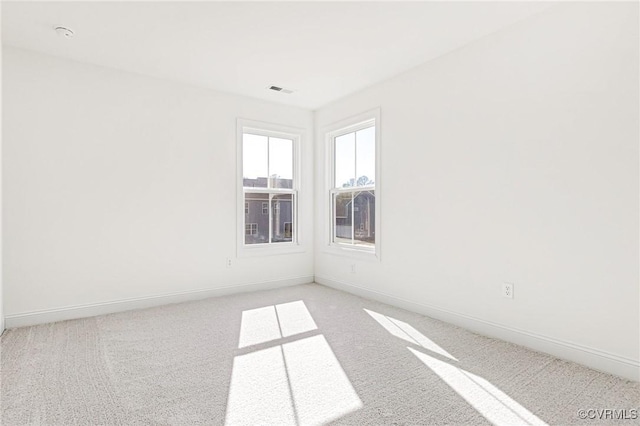 spare room featuring light carpet, visible vents, and baseboards