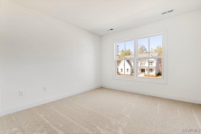 spare room with baseboards, visible vents, and light colored carpet