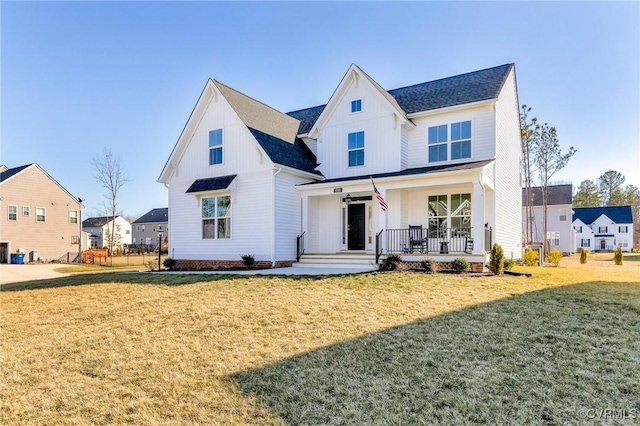 modern farmhouse with board and batten siding, a front yard, covered porch, and roof with shingles