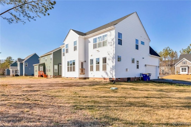 rear view of house with crawl space, a lawn, and an attached garage