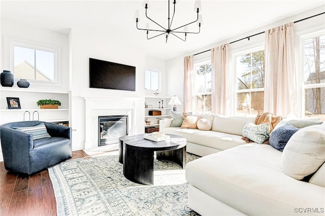 living room featuring a high end fireplace, an inviting chandelier, and wood finished floors