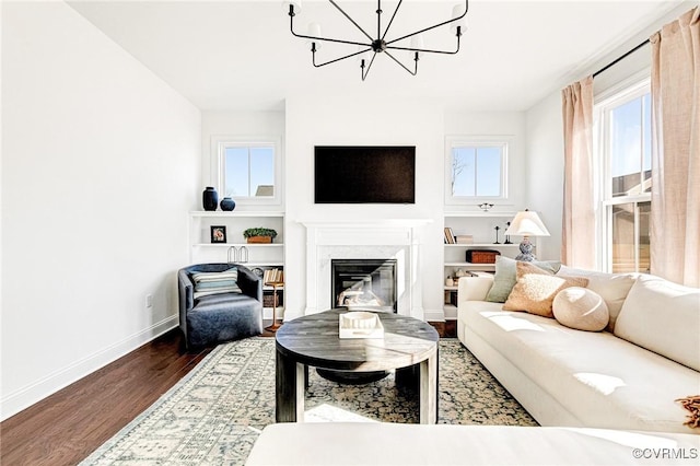 living area with an inviting chandelier, baseboards, wood finished floors, and a high end fireplace