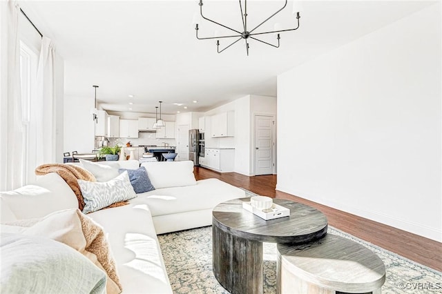 living area featuring baseboards, a chandelier, dark wood-style flooring, and recessed lighting