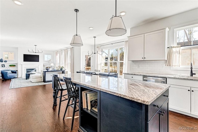 kitchen with stainless steel dishwasher, dark wood-style flooring, a kitchen island, and decorative backsplash