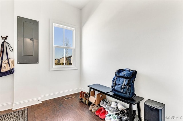 interior space featuring baseboards, electric panel, visible vents, and wood finished floors