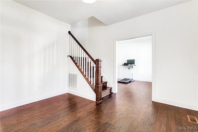 empty room with stairs, wood finished floors, visible vents, and baseboards