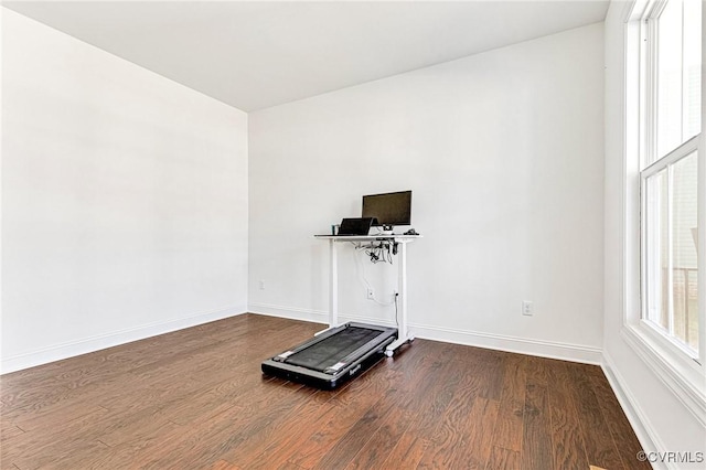 exercise room with dark wood-style flooring and baseboards