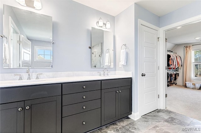 full bathroom with double vanity, a sink, and a walk in closet