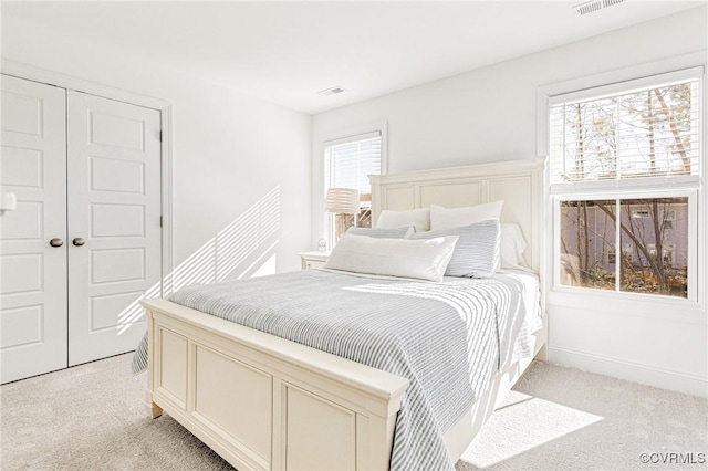 bedroom with baseboards, a closet, visible vents, and light colored carpet