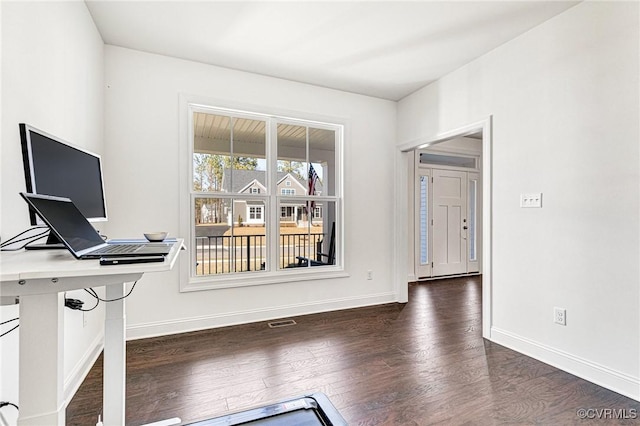 unfurnished office featuring baseboards, visible vents, and wood finished floors