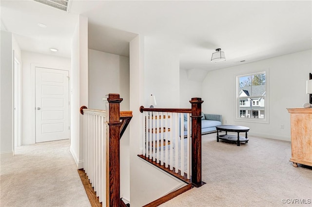 corridor featuring carpet floors, baseboards, visible vents, and an upstairs landing