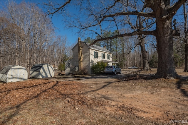 view of home's exterior featuring an outdoor structure, a chimney, and a shed