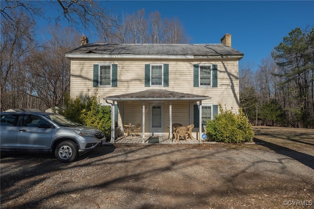 view of front facade with covered porch and a chimney