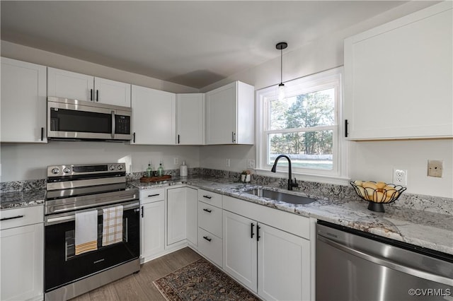 kitchen with appliances with stainless steel finishes, white cabinets, and a sink