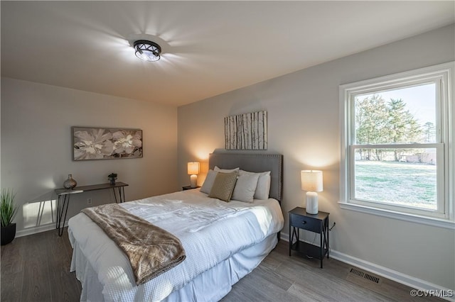 bedroom with baseboards, visible vents, and wood finished floors