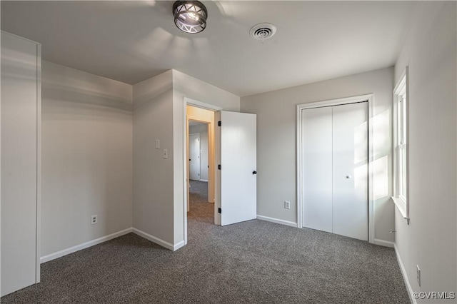 unfurnished bedroom featuring dark colored carpet, visible vents, baseboards, and multiple windows