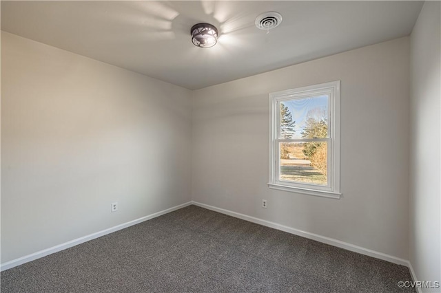 empty room with dark colored carpet, visible vents, and baseboards