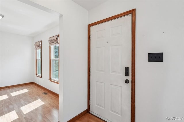 foyer with light wood finished floors, visible vents, and baseboards