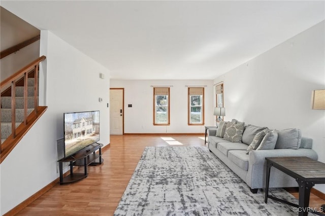 living room with light wood-style flooring, stairway, and baseboards