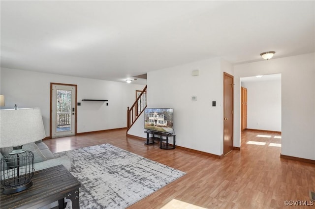 living room featuring light wood-style floors, stairway, and baseboards