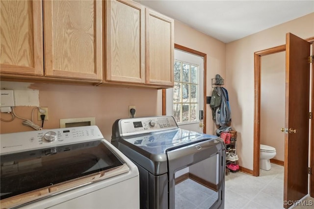 washroom with cabinet space, baseboards, and washing machine and clothes dryer