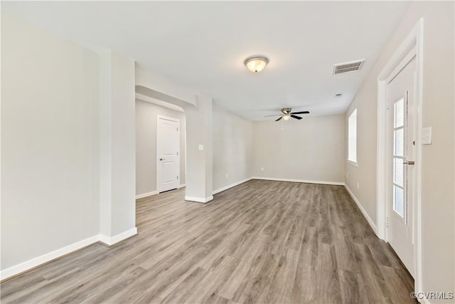 unfurnished room featuring a ceiling fan, visible vents, baseboards, and wood finished floors