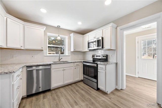 kitchen featuring light wood-style flooring, white cabinetry, stainless steel appliances, and a sink