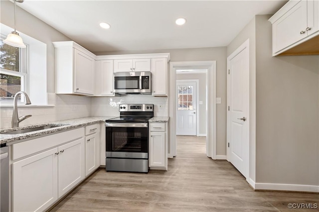 kitchen with appliances with stainless steel finishes, backsplash, a sink, and white cabinetry