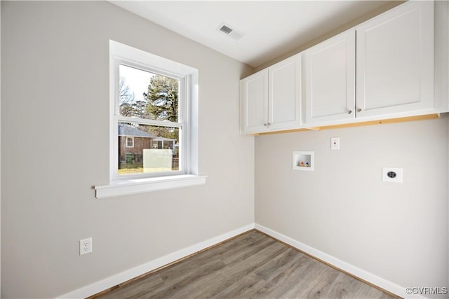 washroom with hookup for a washing machine, cabinet space, light wood-style flooring, electric dryer hookup, and baseboards