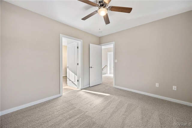 carpeted empty room featuring ceiling fan and baseboards